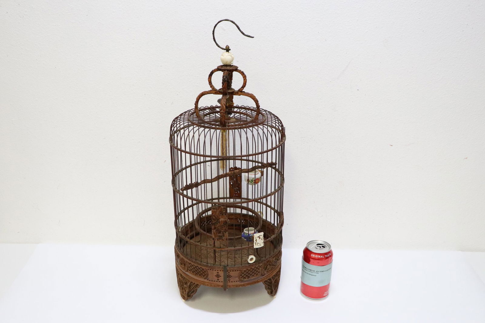 A Chinese antique bamboo carved bird cage: A Chinese antique elaborately carved bamboo bird cage with bone carved finial and 2 vintage porcelain bird feeders, the base of the cage carved with dragon motif decoration in relief, 23.5"Hx9.5"dia