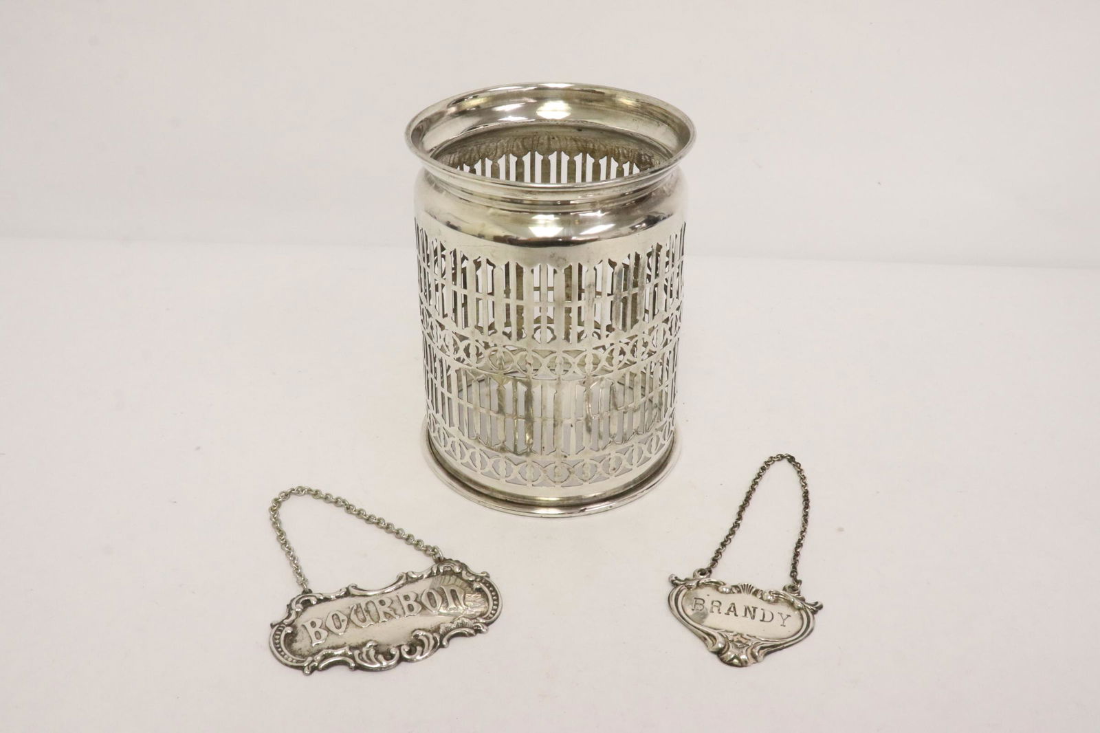 2 sterling wine labels, & a sterling wine bottle holder: 3 pieces; 2 sterling wine labels (1.4"x1.8", 1.45"x2.85"), and a sterling wine bottle holder (4.9"Hx3.75"dia)