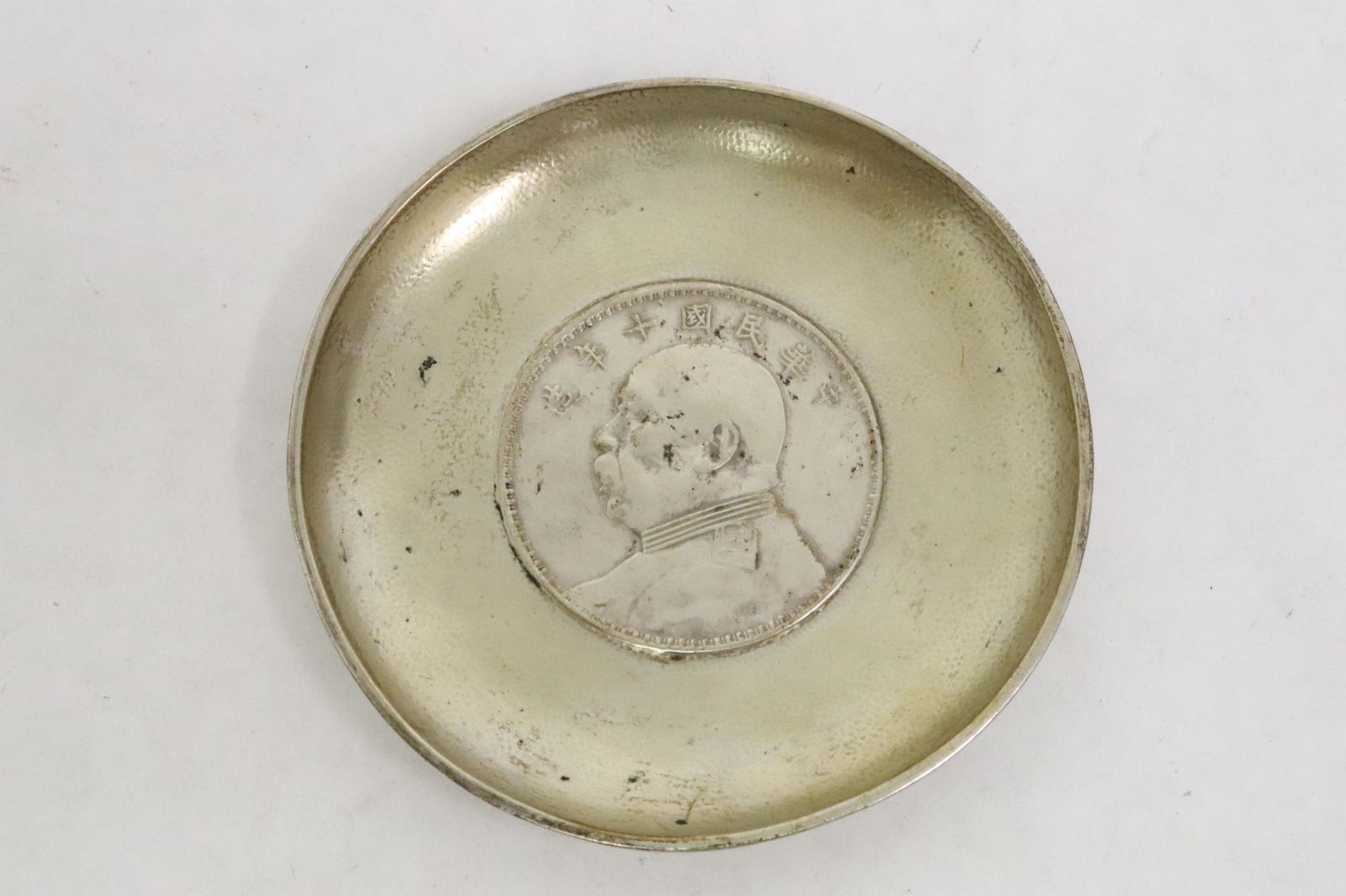 A silver dish with one Chinese coin at center (1 of 7)