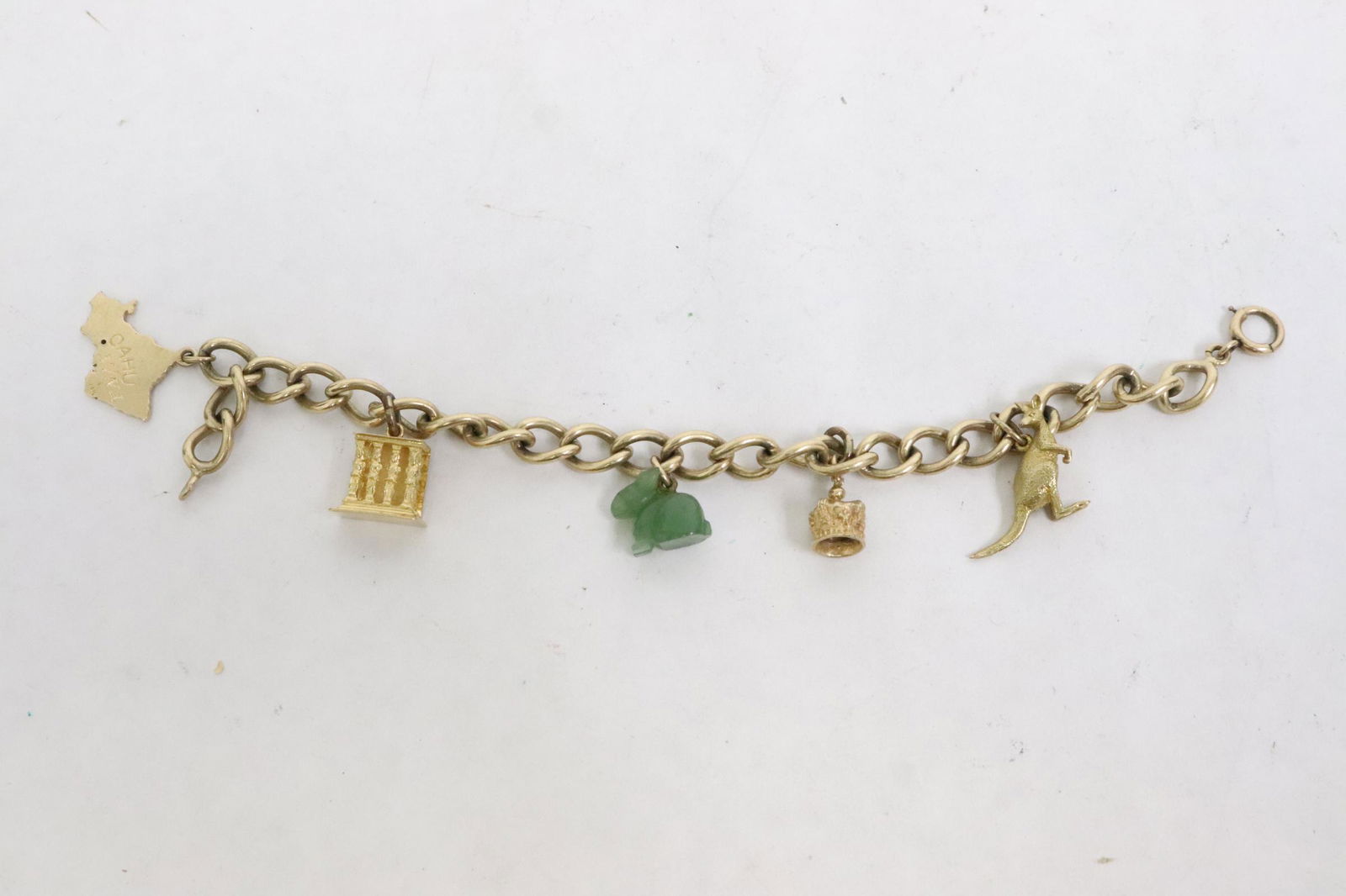 A 14K Y/G charm bracelet: A 14K Y/G charm bracelet (7.5"L) with one 18K, two 9K charms, and a green stone charm, total wt. 31.3gm