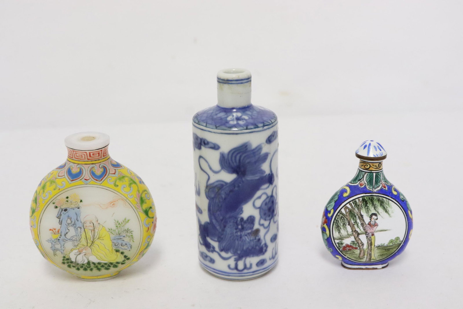 3 snuff bottles: 3 snuff bottles; a blue and white (3.5"x1.4"dia), enamel on Peking glass (2.4"x2"x1") and an enamel on copper example (2.25"x1.5"x0.8")
