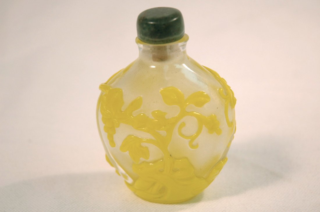 A yellow overlay on clear peking glass snuff btl: A beautiful yellow overlay on clear peking glass snuff bottle depicting squirrel eating grapes on grapevine (3.35"H)