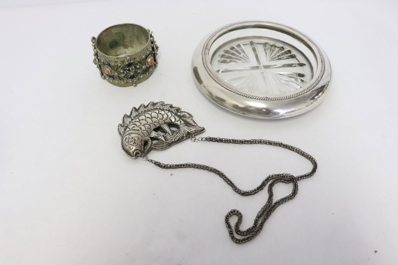 3 pieces: 3 pieces; a sterling rim ashtray (1.8"x2.6"dia), a silverplate fish (3.5"L) with necklace, and an enamel on silverplate cuff (1.15"x6.8"dia)