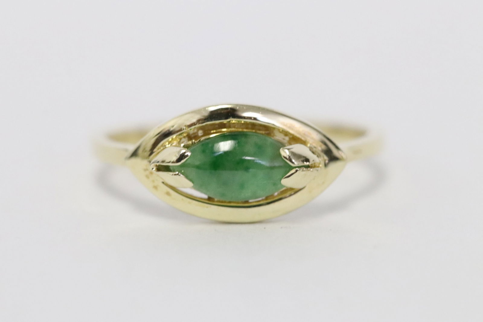 A 14K Y/G jadeite pinky ring: A 14K Y/G pinky ring, center a brilliant apple green jadeite measure approx. 6.0x4.1mm, size 5