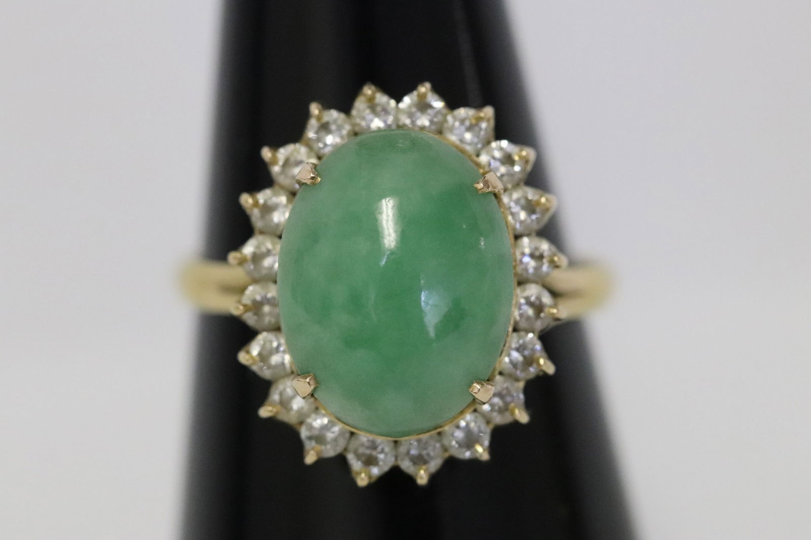A marked 75% Y/G ring w/ jadeite cabochon: A marked 75% (18K) Y/G ring set with an apple green jadeite cabochon measures approx. 12.8x10x3.8mm, wt. 3.4gm, size 7