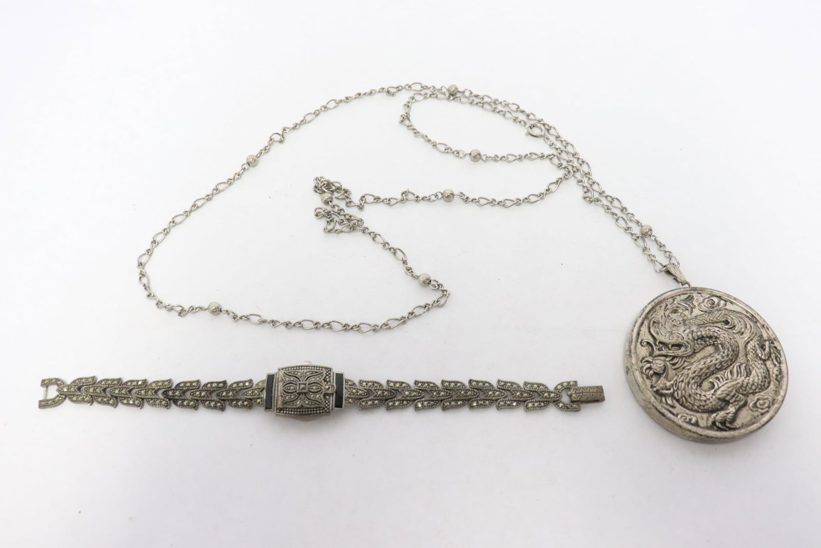 2 pieces: 2 pieces; a Reed and Barton sterling pocket mirror with dragon motif decoration in relief (necklace does not test positive for silver) (0.25"x2.16"dia), and a sterling wrist watch with marcasite