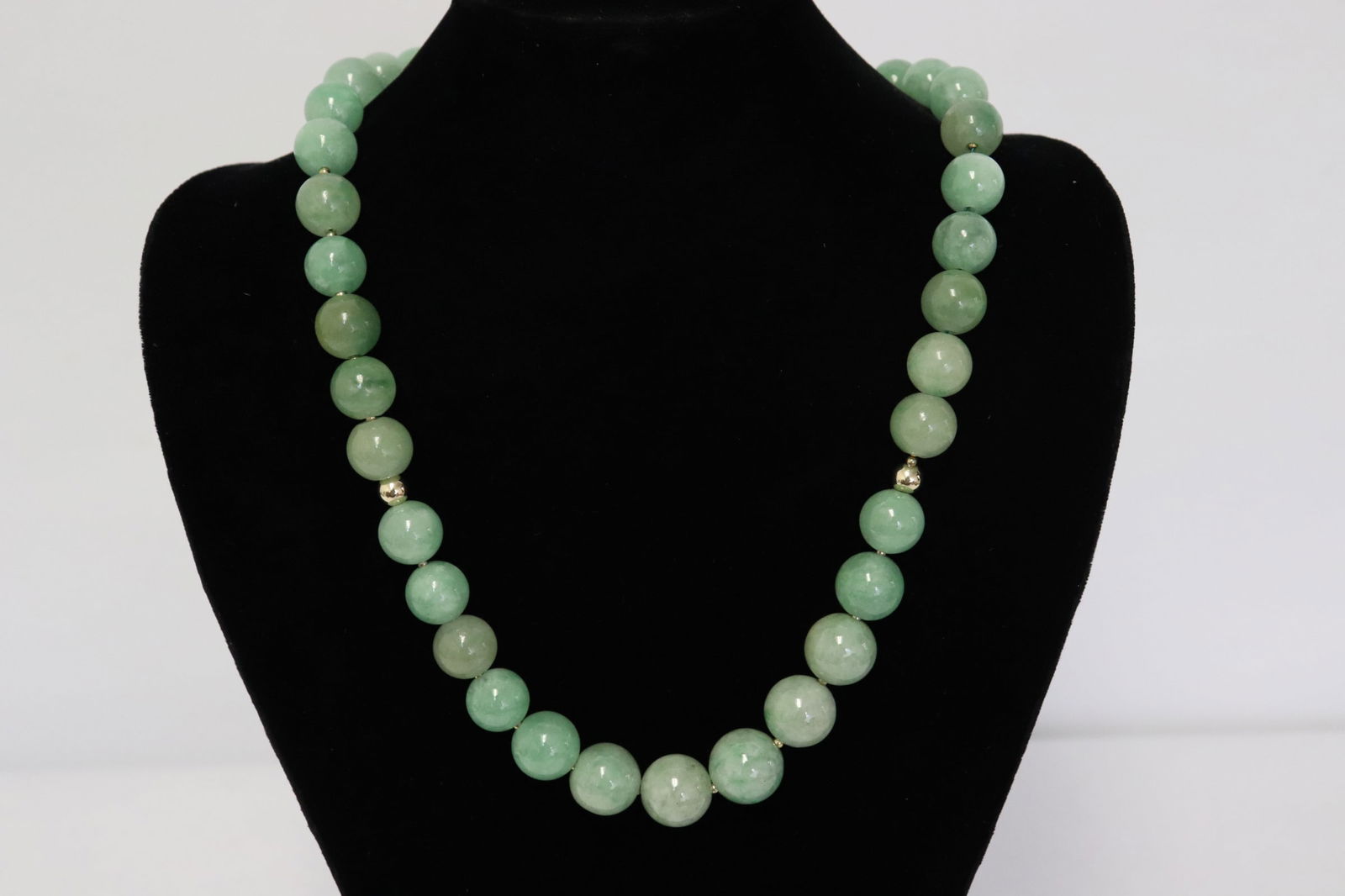 A jadeite bead necklace w/ 14K gold beads & clasp: A jadeite bead necklace with four 14K gold beads, and large 14K Y/G ball clasp, the small yellow metal bead can not be tested due to size, jadeite bead measures approx. 12 - 16 mm diameter