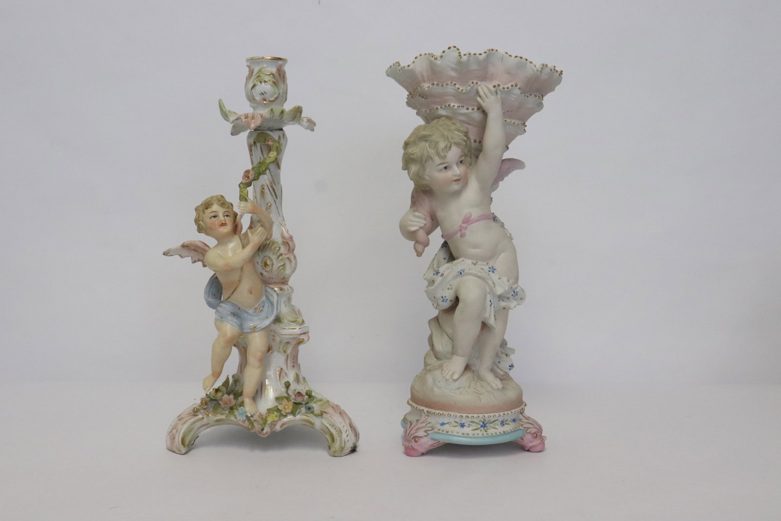 2 European antique porcelain candle holders: 2 European antique porcelain candle holders with angel motif bases, 11.1"H, 11.4"H