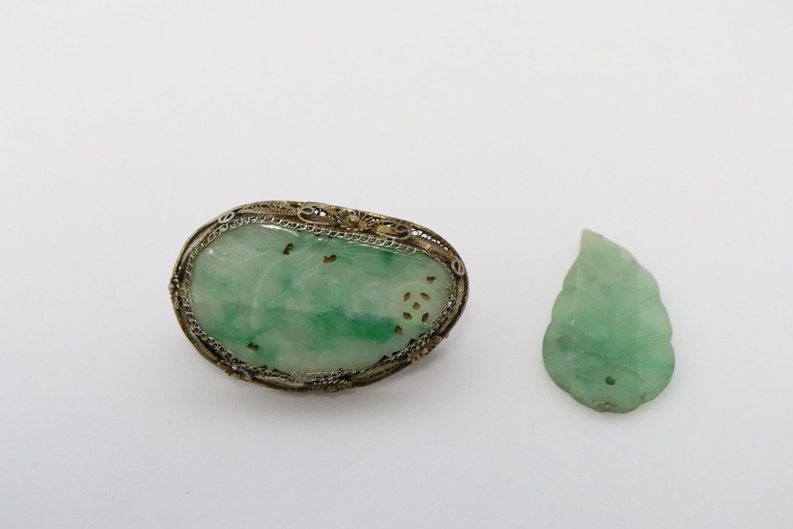 2 jadeite pieces: 2 pieces; antique Chinese silver framed jadeite brooch (jadeite crack, measure approx. 30x19mm), and a leaf motif jadeite ornament (hairline) (0.1"x1.2"x0.65")