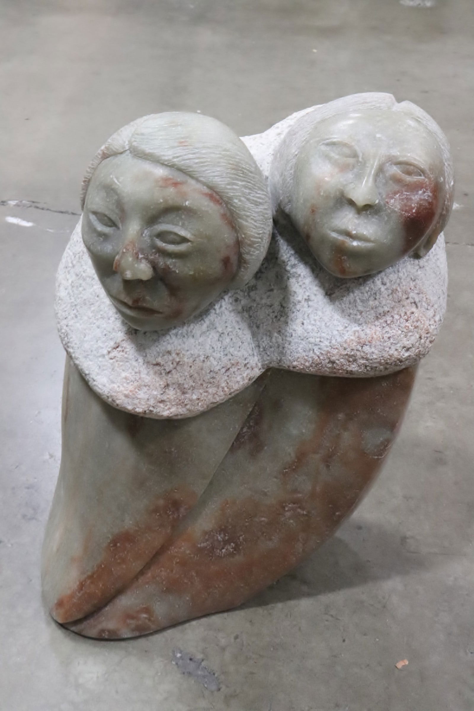 A stone carving depicting 2 figures, signed (1 of 9)