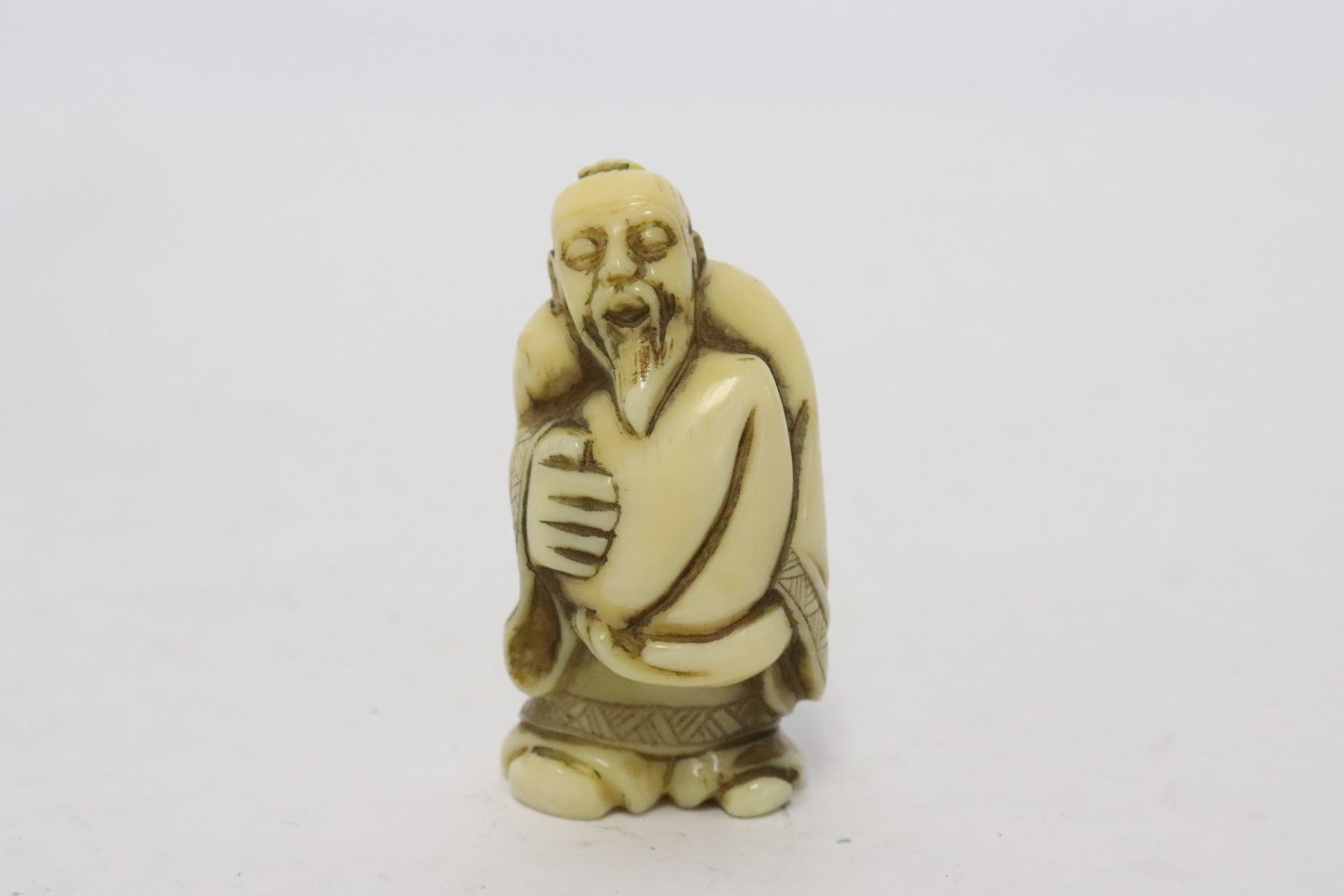 Japanese bone carved netsuke: Japanese bone carved netsuke of old man holding a peach, 1.8"H