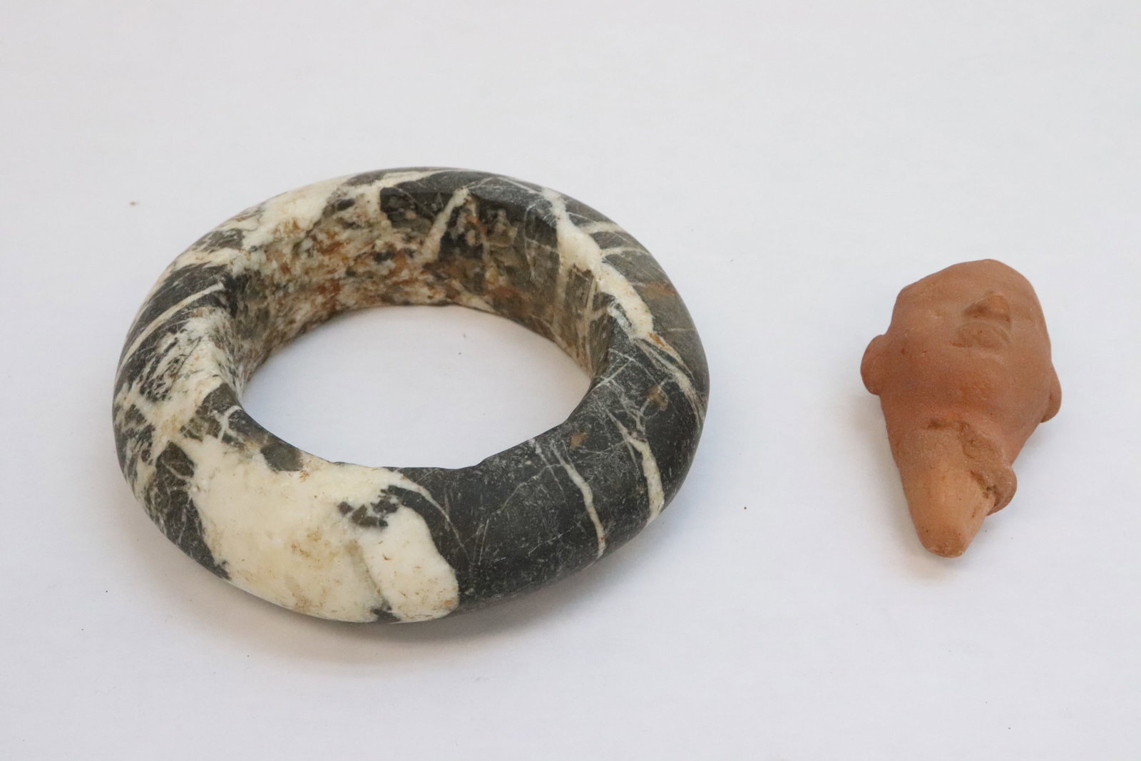 Antique stone bangle, and a pottery head: Antique stone bangle (1.3"x4.5"dia), and a pottery head (2.6"H)