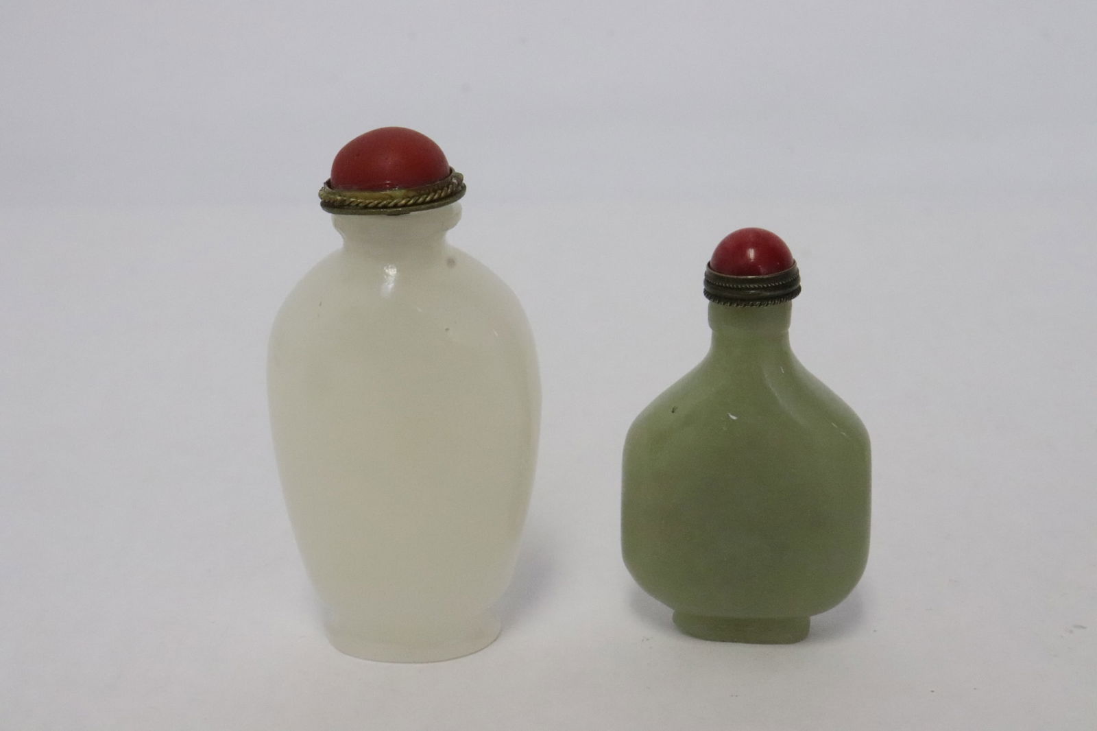 2 snuff bottles: 2 snuff bottles; one celadon jade (2.4"x1.35"x0.65"), one white Peking glass (2.9"x1.4"x0.9")