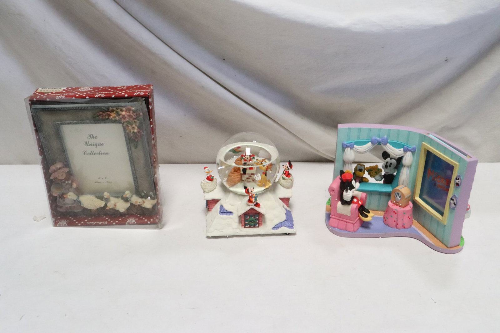 3 pieces: 3 pieces; Mickey and framed dressing room (7"H), a Pluto/ Goofy snowglobe (6.7"H), and a picture frame with cartoon characters (9"x7.3")