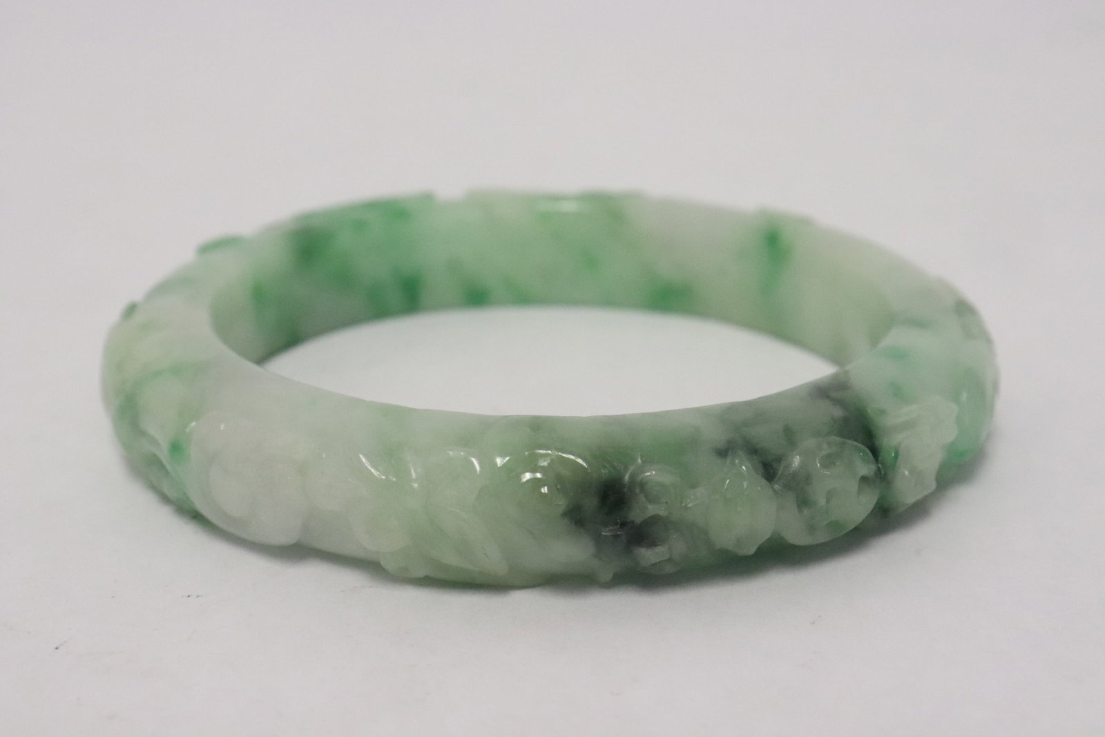Chinese large apple green jadeite carved bangle: Chinese large apple green jadeite carved bangle, top carved with 8 treasure items in relief, 0.66"x3.82"dia