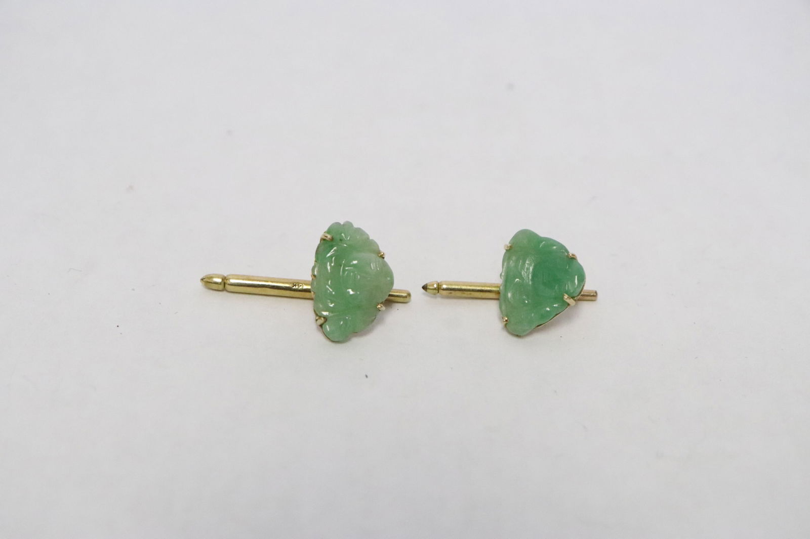 Pair 14K rose gold jadeite studs: Pair 14K rose gold studs, each set with an apple green jadeite carved deity, wt. 3.6gm