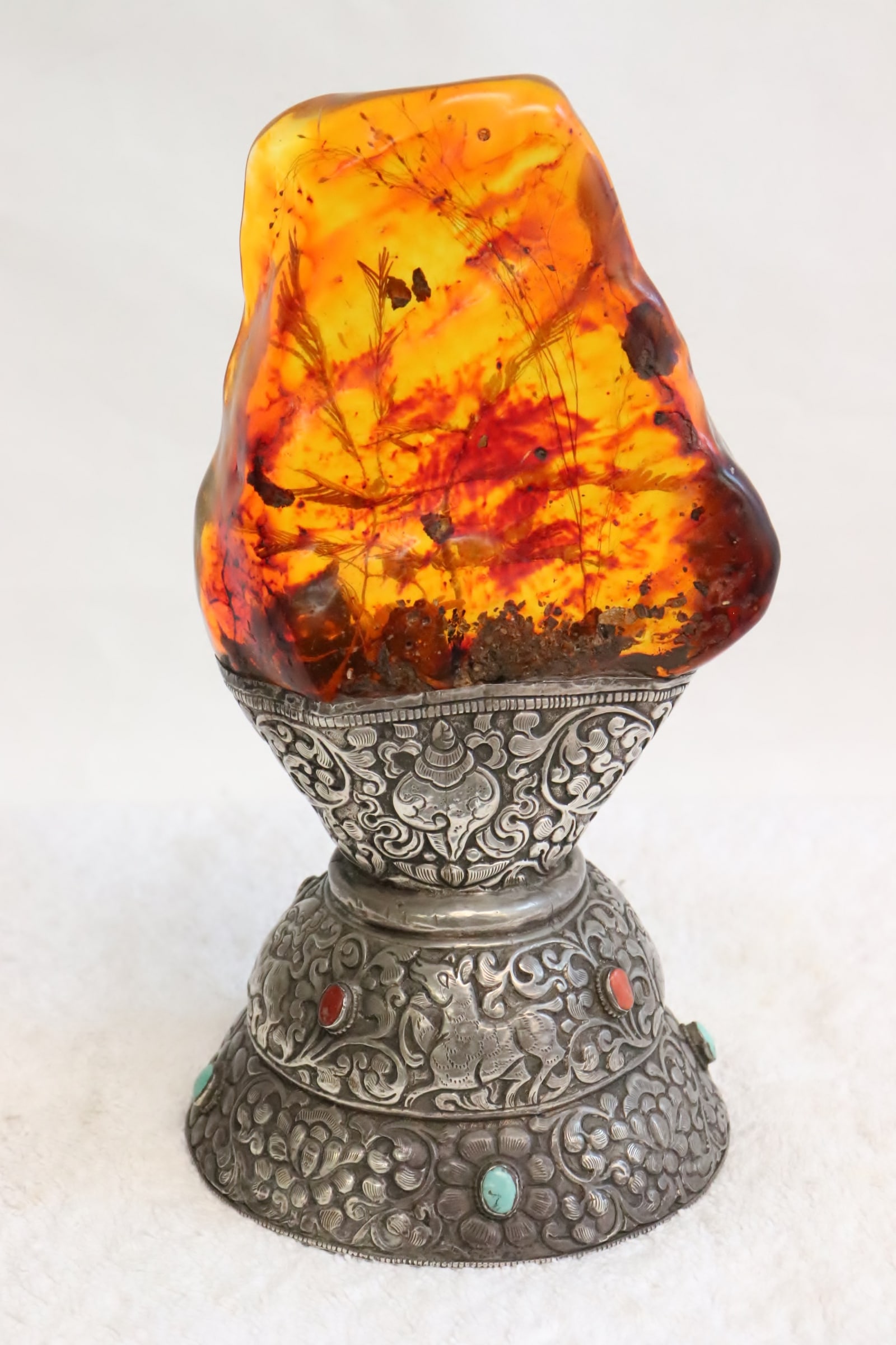 Tibetan amber ornament w/ silver base: A rare Tibetan amber ornament with ornate silver base (tested positive for silver, content unknown, total wt. 1325gm), the base engraved with animal and flower decoration, decorated with coral and tur