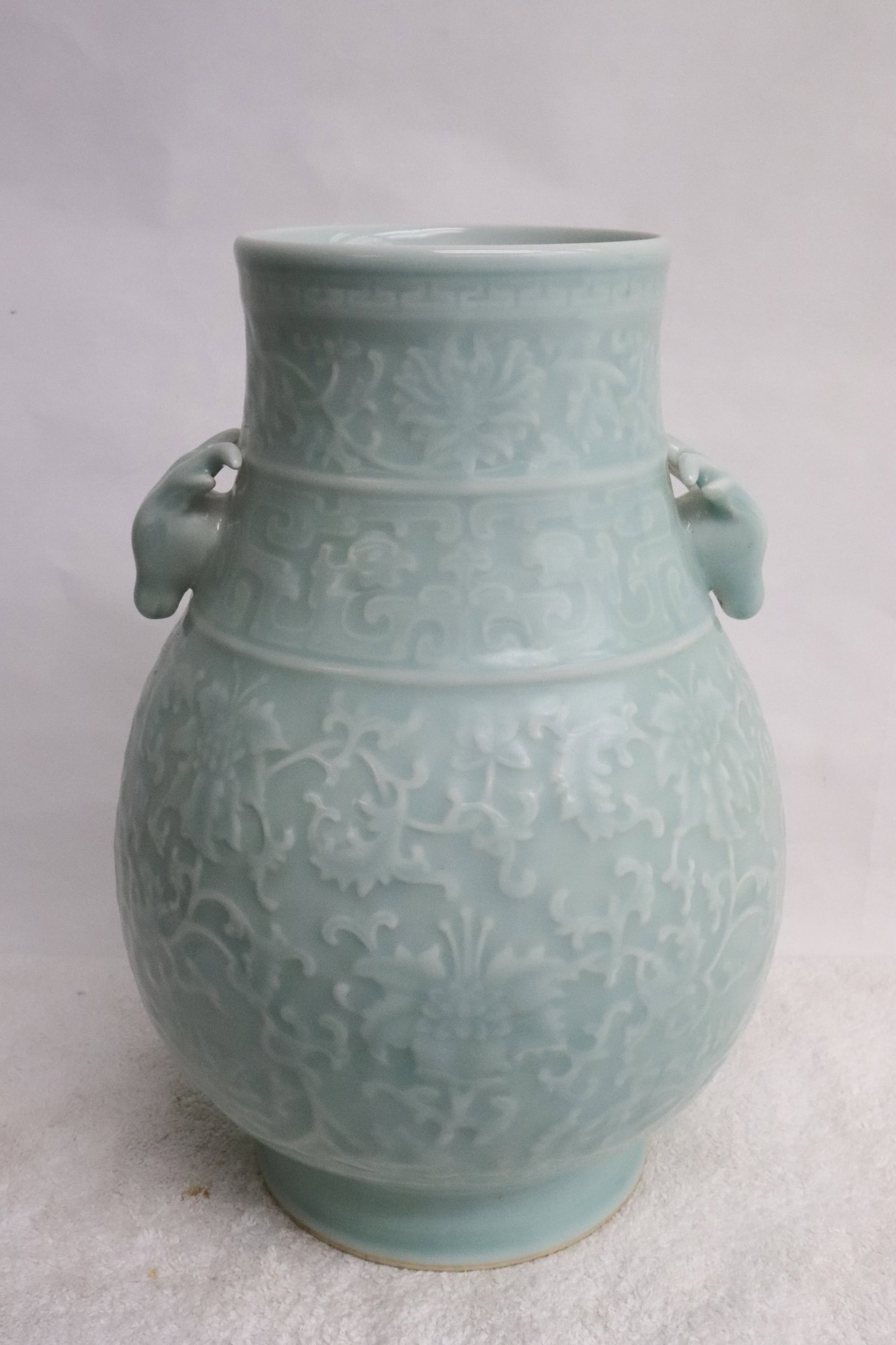 Fine light celadon porcelain jar: Fine light celadon porcelain jar with intertwin flower and leaves decoration in relief, with ram motif handles, 11.8"x8.2"dia
