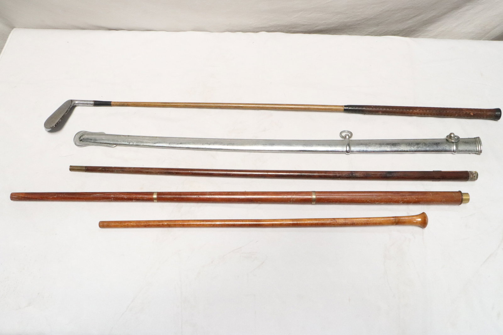 5 pieces: 5 pieces; wood handle golf club (39"L), a wood baton (35"L), 2 wood canes (24.2"L, 32"L) (no cane top), and a scabbard for cavalry sword (33.3"L)