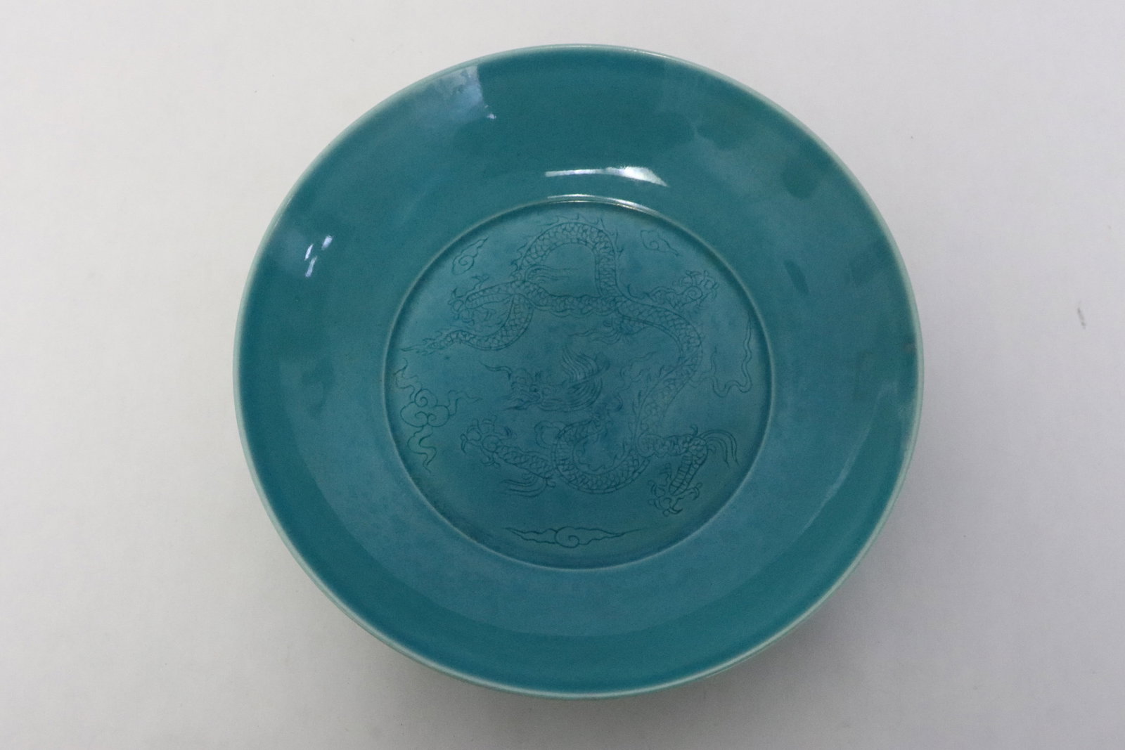 Chinese bright blue glazed porcelain plate: Chinese bright blue glazed porcelain plate, center and outer border incised with dragon and cloud, 1.75"x8.1"dia