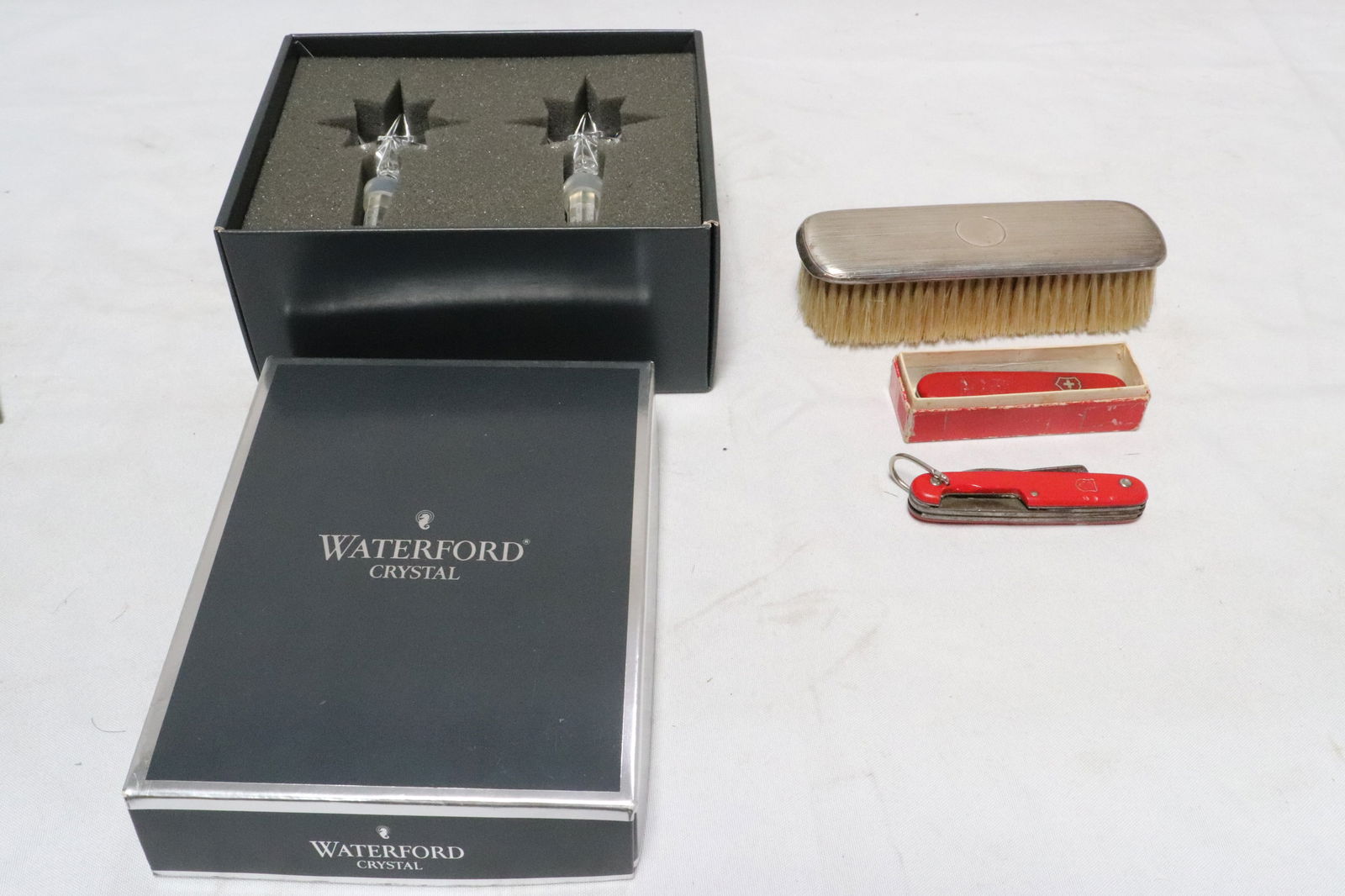 5 pieces: 5 pieces; sterling brush (6.6"x2"x1.5"), and 2 Swiss Army pocket knives (0ne case chip) (3.6"L, 3.7"L), and 2 Waterford wine bottle stoppers (4.4"H ea)