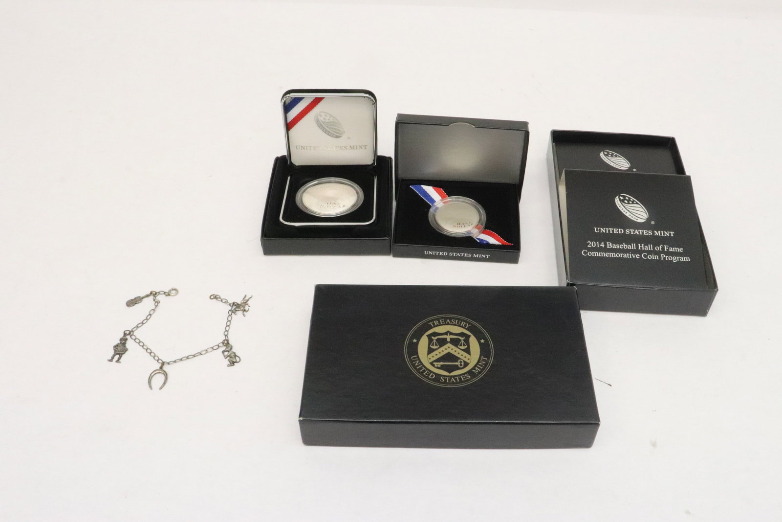 2 silver baseball hall of fame coins, & a sterling bracelet: 3 pieces; an 1-ounce silver baseball hall of fame coin (0.1"x1.5"dia), and a half-ounce silver baseball hall of fame coin (0.08"x1.15"dia), and a sterling charm bracelet (7.7"L)
