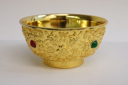 A yellow bronze bowl with decoration in relief