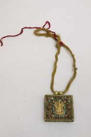 Tibetan gilt metal pendant set with portrait of deity