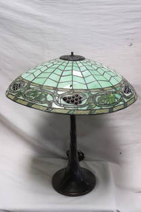 A cast metal based table lamp with leaded glass shade: A cast metal based table lamp (27.35"H) with leaded glass shade (6.1"x21.8"dia), shade 2 panels have chips