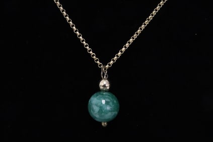 A jadeite bead attached to a gold filled necklace