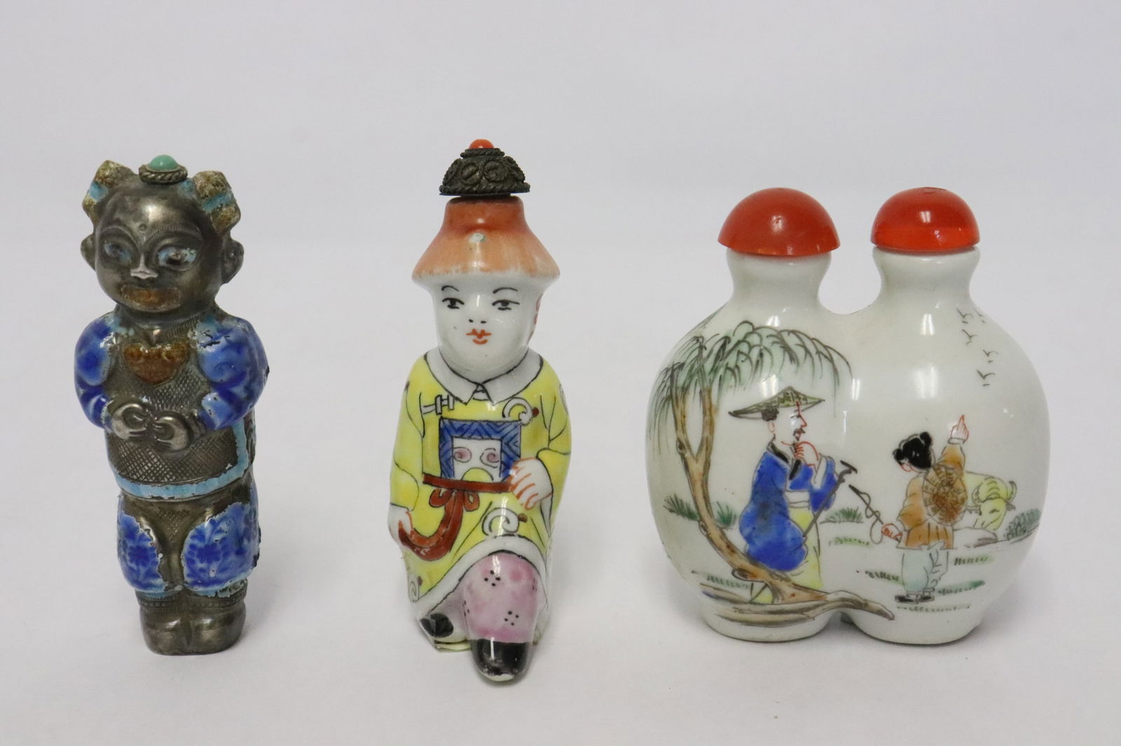 3 Chinese snuff bottles: 3 Chinese snuff bottles; 2 porcelain (2.85"x1.35"x1.1", 2.65"x1.6"x2.35"), and one enamel on silver (tested positive for silver, wt. 27.5gm) (2.9"H)