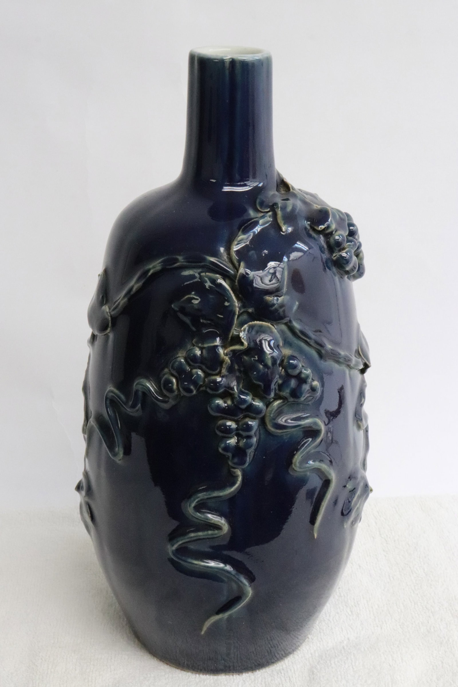 Chinese blue glazed porcelain wine bottle: Chinese blue glazed porcelain wine bottle with grape motif decoration in high relief, 12.25"x5.85"dia