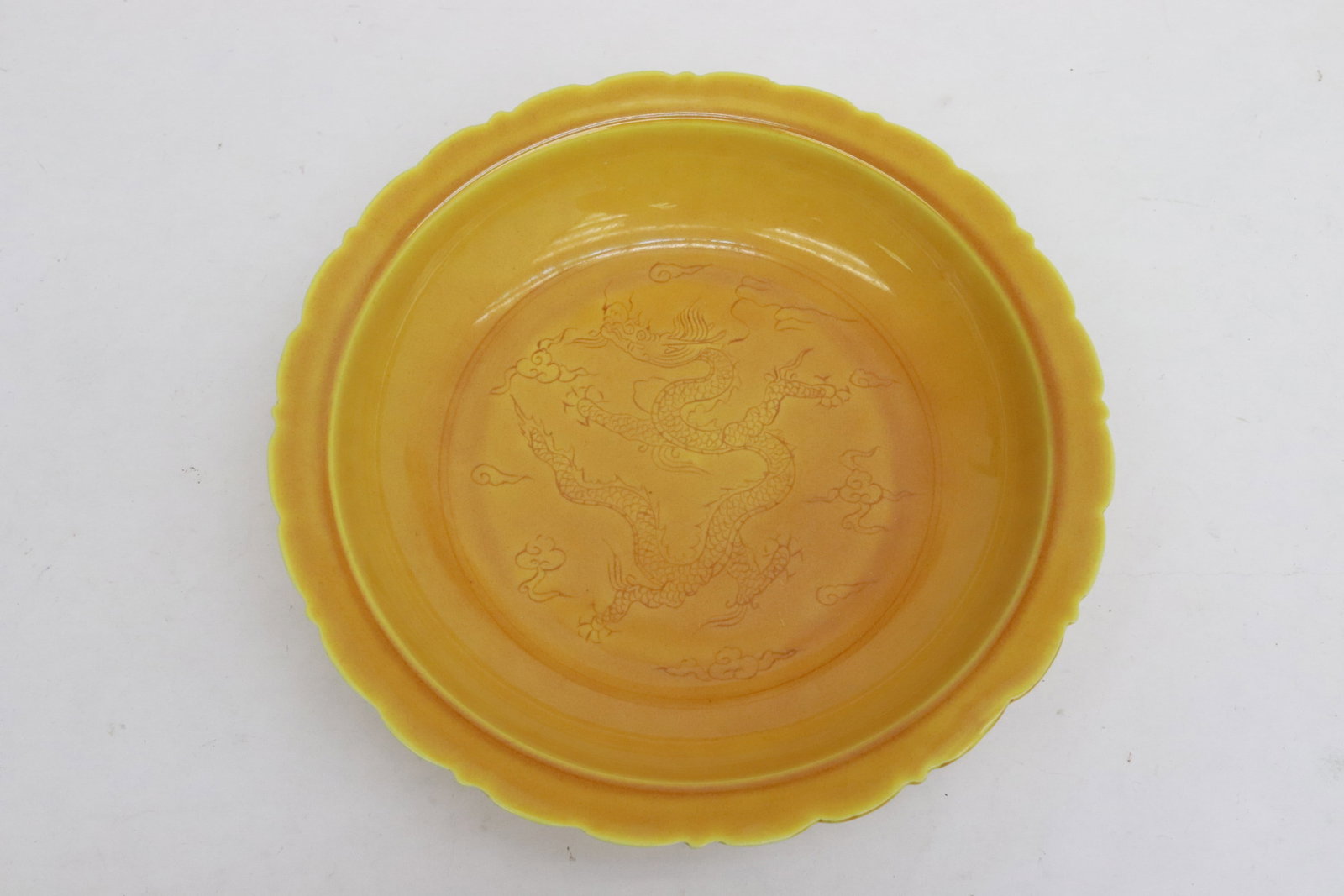 A yellow glazed porcelain plate: A yellow glazed porcelain plate with embossed dragon motif decoration, 2"x8.65"dia