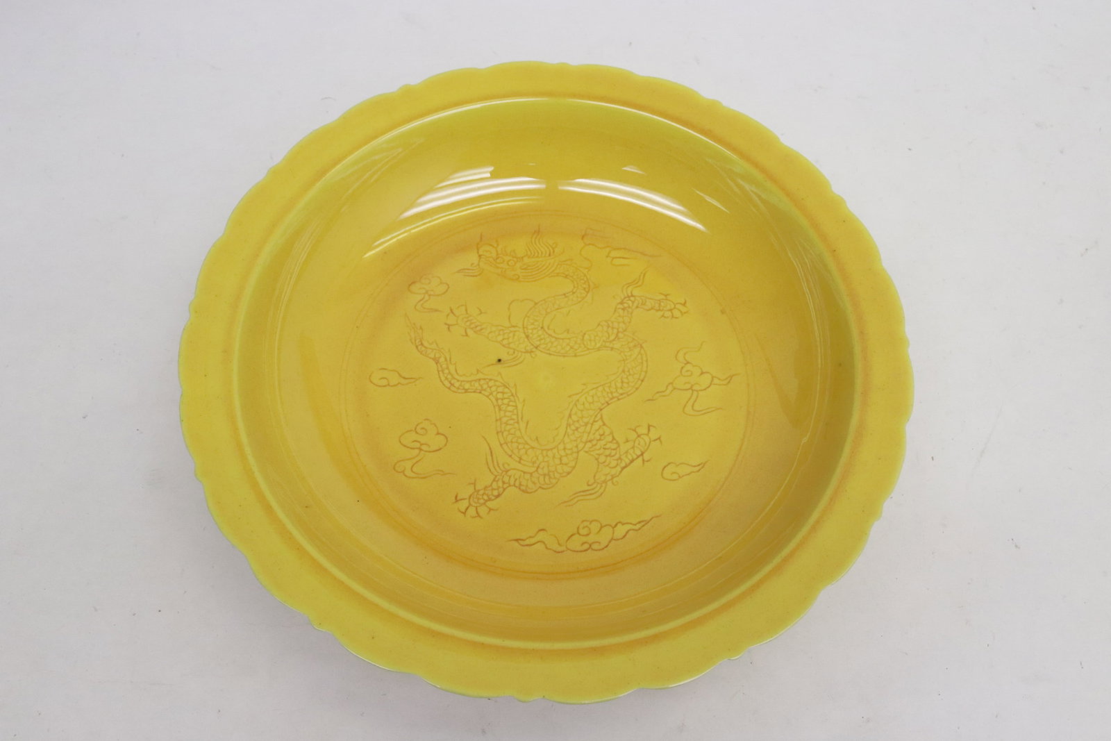 A yellow glazed porcelain plate: A yellow glazed porcelain plate embossed with dragon motif decoration, 1.9"x8.65"dia