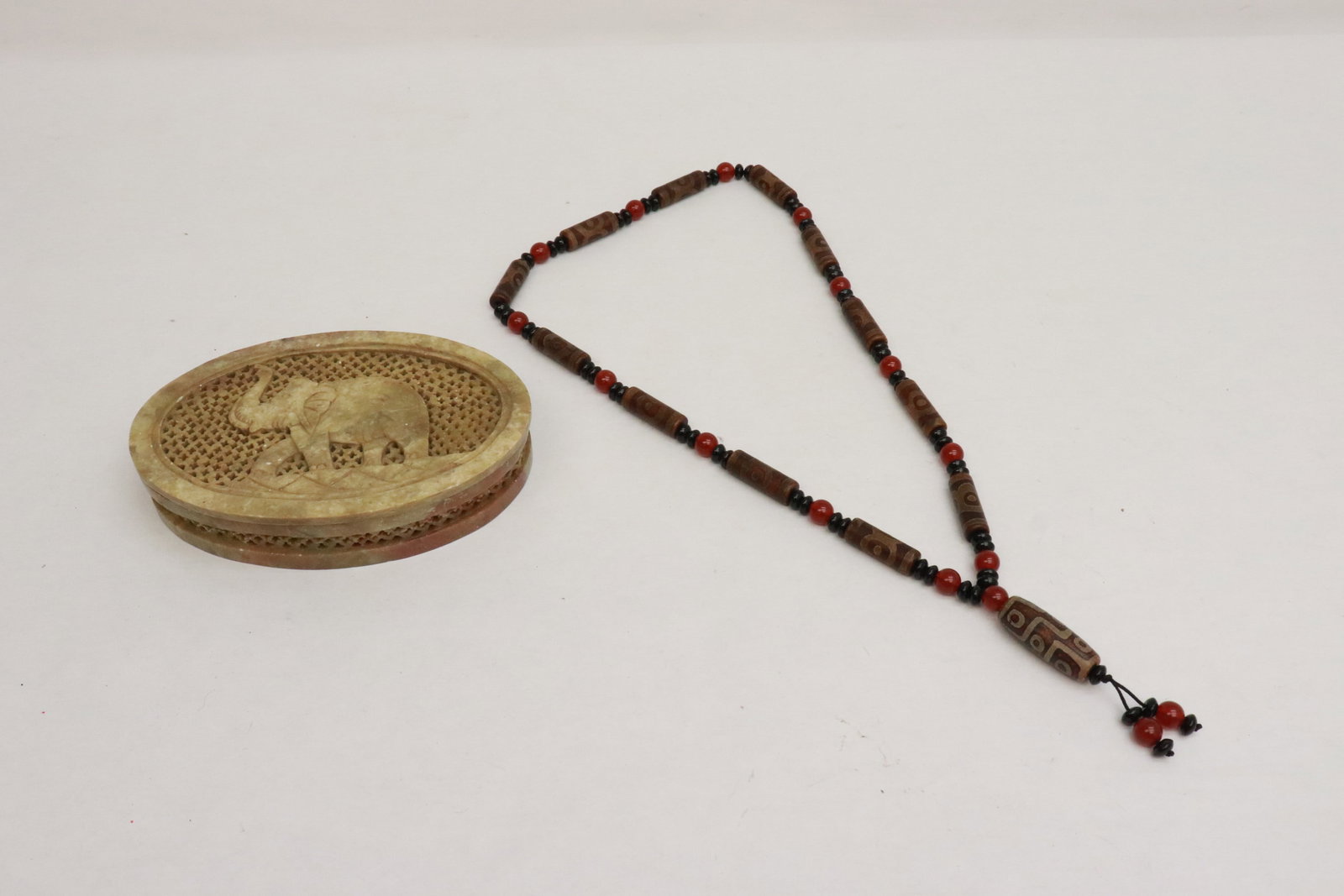 a soapstone carved box, and a bead necklace: 2 pieces; a soapstone carved box (1.15"x4.15"x6.15"), and a dzi bead (1.15"x0.35"dia - 1.5"x0.6"dia) style bead necklace (28.5"L)