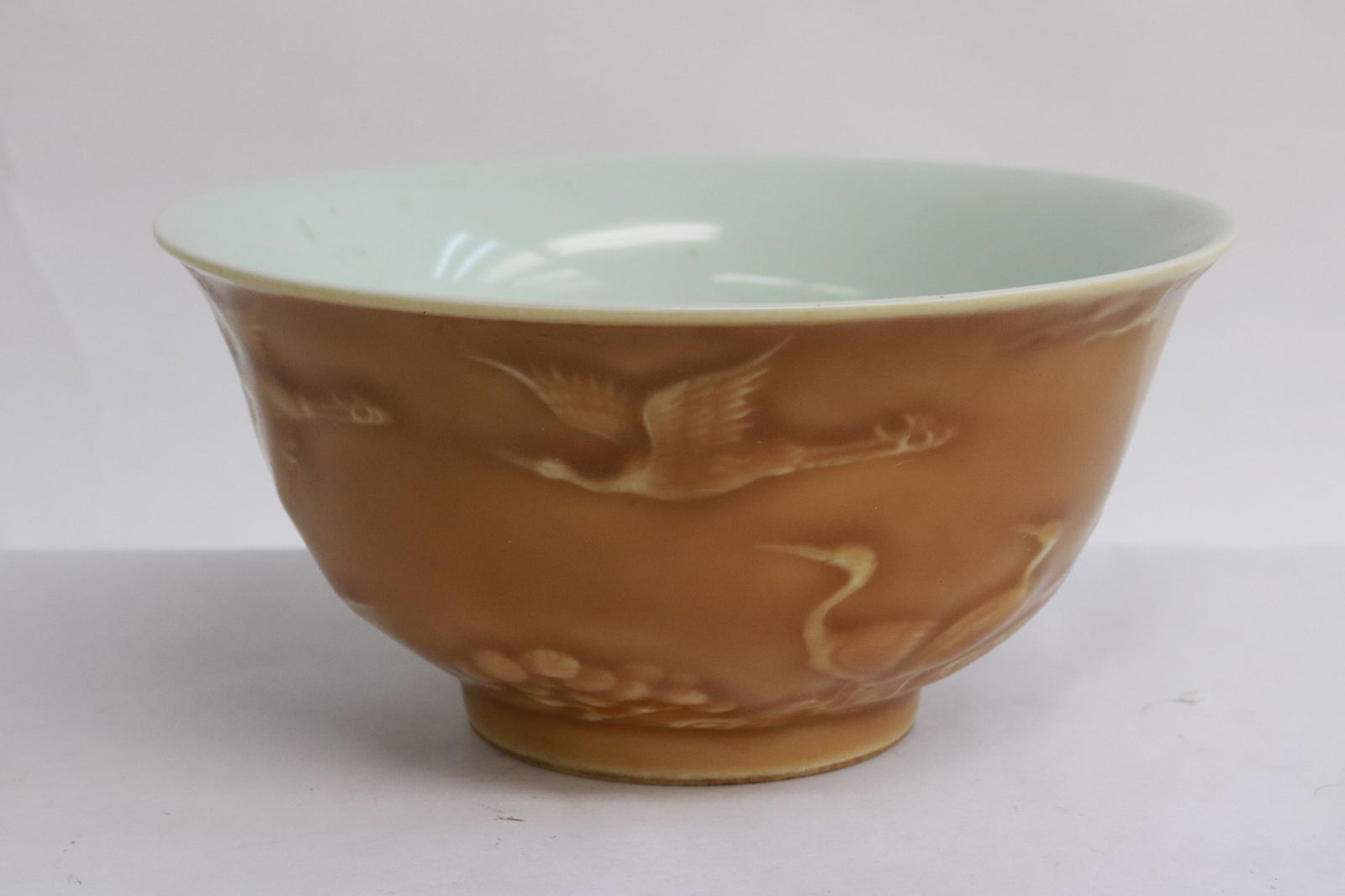 A light brown glazed porcelain bowl: A light brown glazed porcelain bowl with birds and flowers motif decoration in relief, 3.2"x6.2"dia