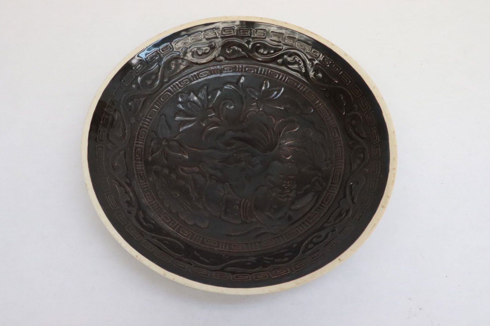 A brown glazed porcelain plate: A brown glazed porcelain plate with embossed decoration, 1.65"x8.15"dia