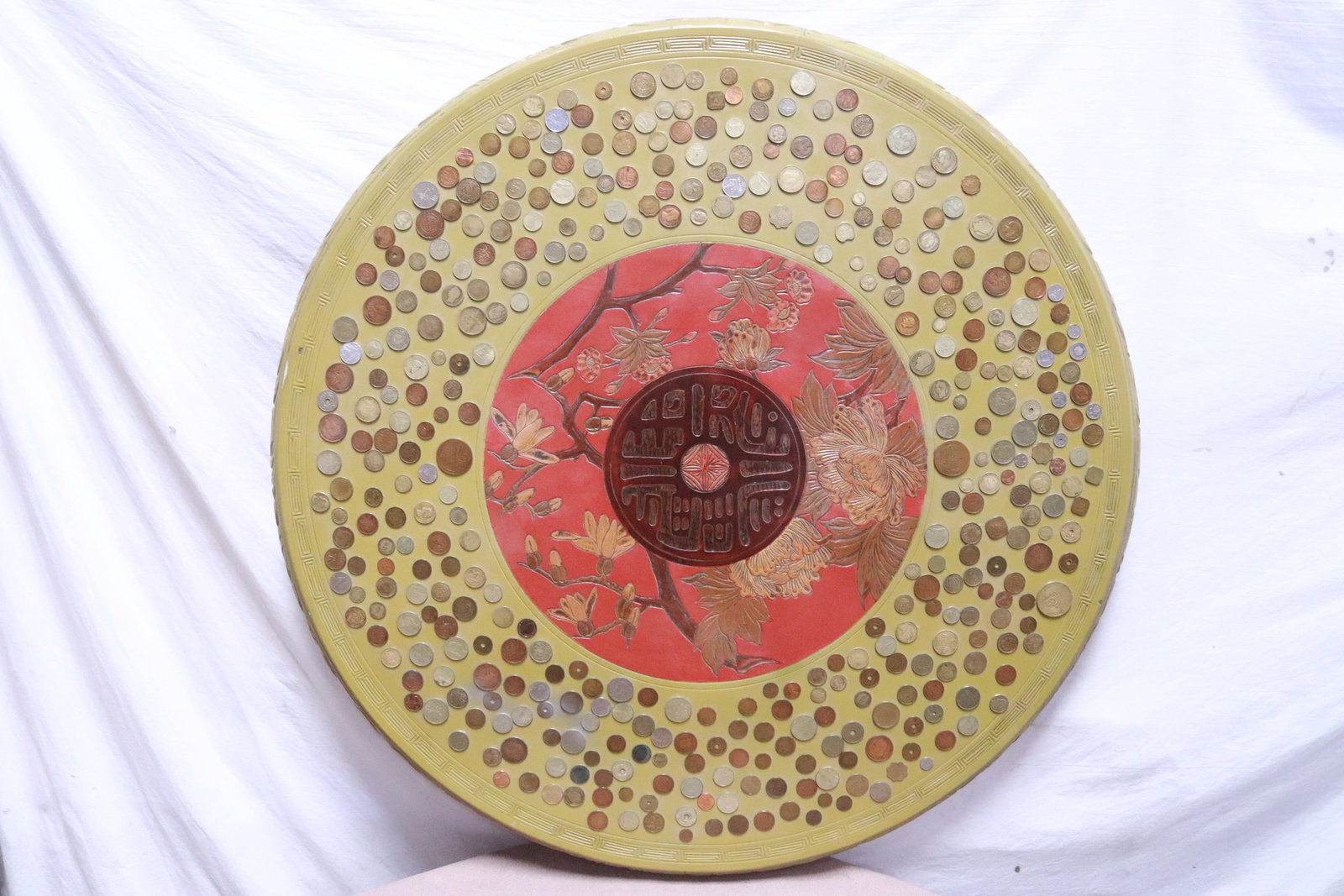 A painted wood wall hanging decorated w/ coins: A round painted wood wall hanging decorated with hundreds of coins, US and foreign, 2.5"x37.5"dia