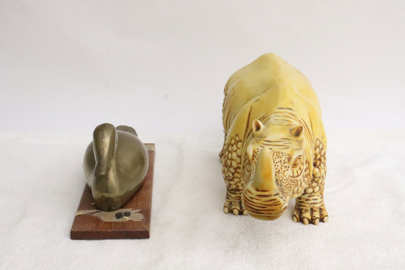 a brass/ bronze duck, and a molded model of rhino: 2 pieces; a brass/ bronze duck (3.7"x8.6"x2.65"), and a Molded model of rhino (5.75"x12.5"x4.4")