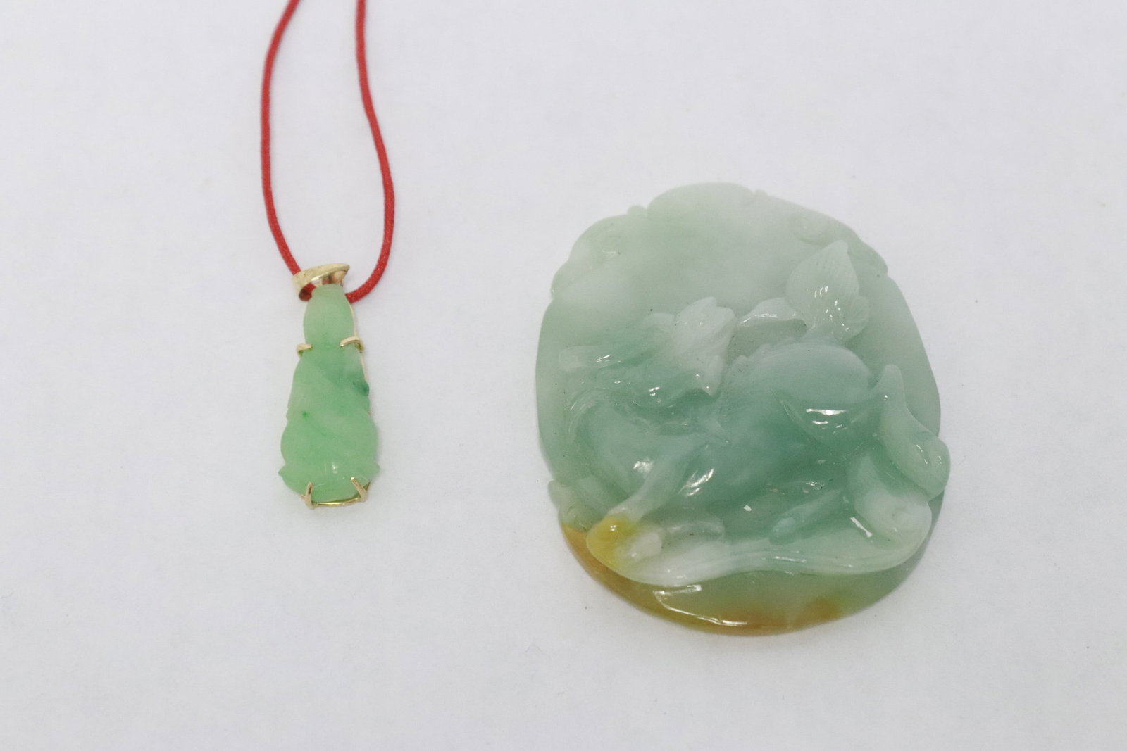 a jadeite carved pendant, & a jadeite carving w/ 14K hook: 2 pieces; a jadeite carved pendant (2.1"x1.65"x0.35") with decoration in relief, and a jadeite carved Buddha with 14K Y/G hook (1.1"x0.35"x0.18")