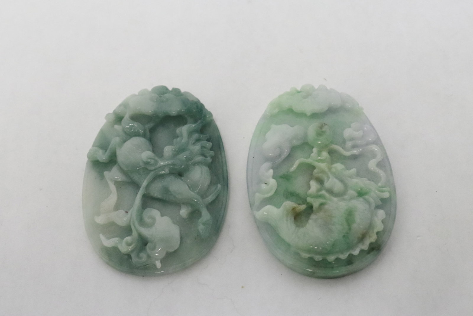2 jadeite carved pendants: 2 fine jadeite carved pendants with decoration in relief, 2.18"x1.5"x0.35", 2.2"x1.6"x0.25"