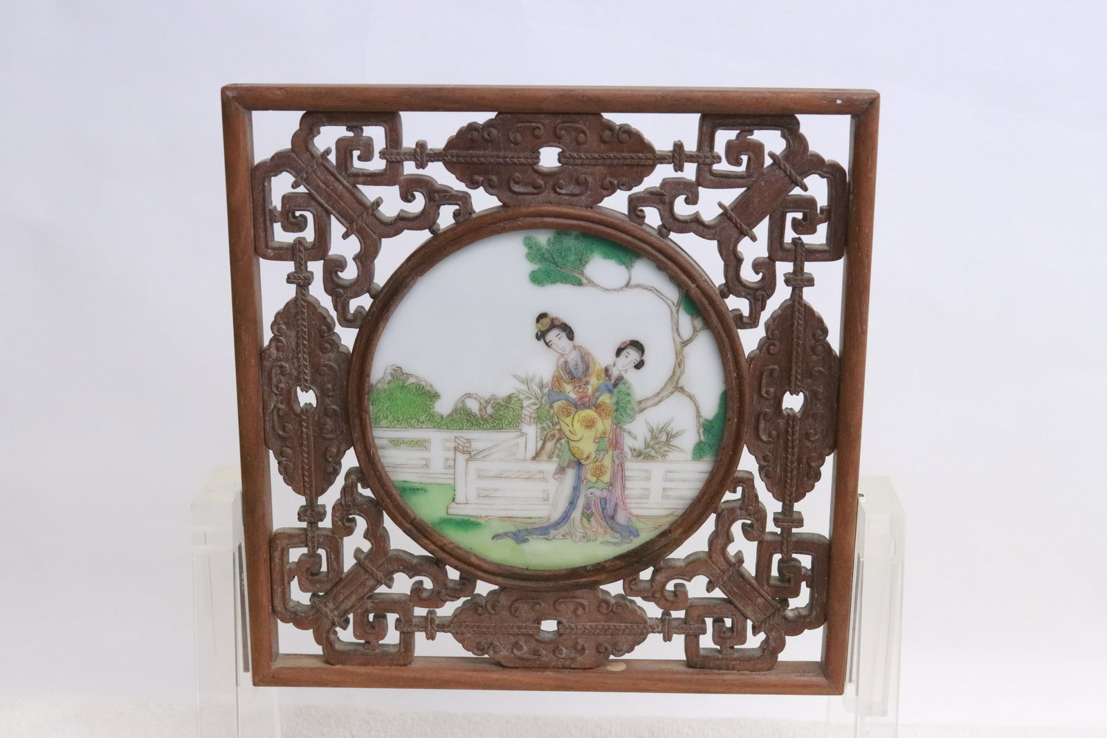 A framed porcelain round plaque on Lucite stand: A framed porcelain round plaque (7.3"x7.25"x0.5") on Lucite stand (6.68"x8.2"x3.15")