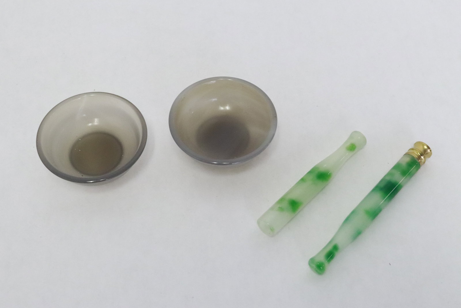 2 jadeite like cigarette holders, 2 agate wine cups: 2 jadeite like cigarette holders (3.05"x0.4"dia, 3.7"x0.4"dia), 2 agate wine cups (0.83"x2.2"dia ea)