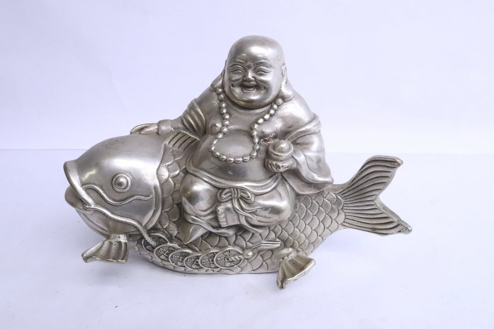 A white metal sculpture to depict Hotei on fish: A white metal sculpture to depict Hotei on fish, 5.9"H