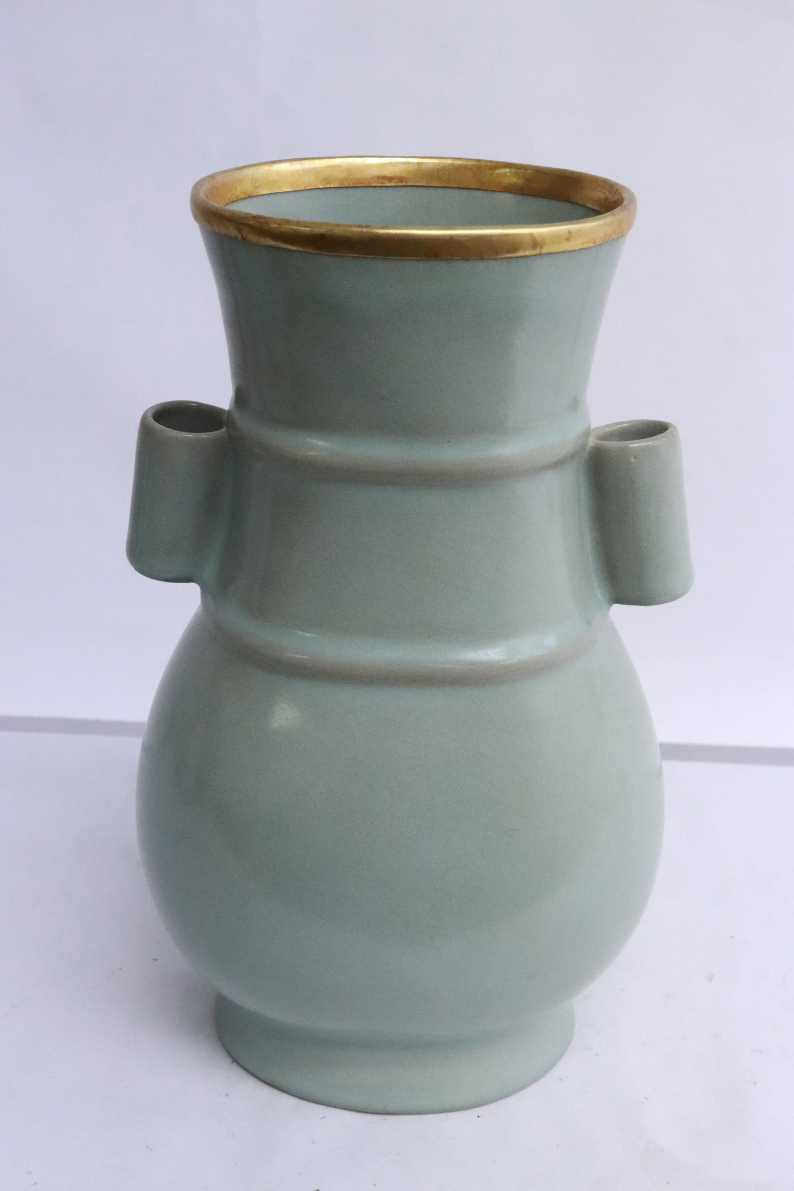 A celadon porcelain handled vase: A celadon porcelain handled vase with gold tone rim, 8.85"x5.4"x4.5"