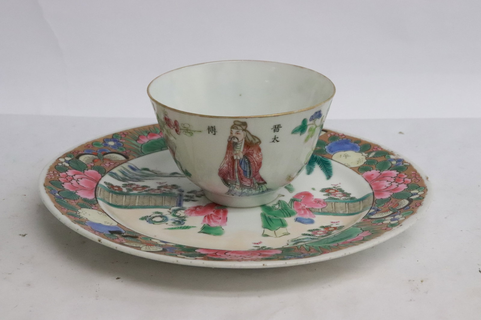 2 antique famille rose porcelain pieces: 2 pieces; antique famille rose plate (edge small chip, painting worn) (0.75"x7.3"dia), and an antique famille rose tea cup (hairline) (2.2"x3.4"dia)
