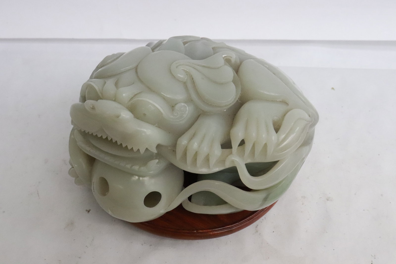 A large Chinese light celadon jade carving: A large Chinese light celadon jade carving depicting fulion holding a ball, 3.9"x6.8"x5.3"
