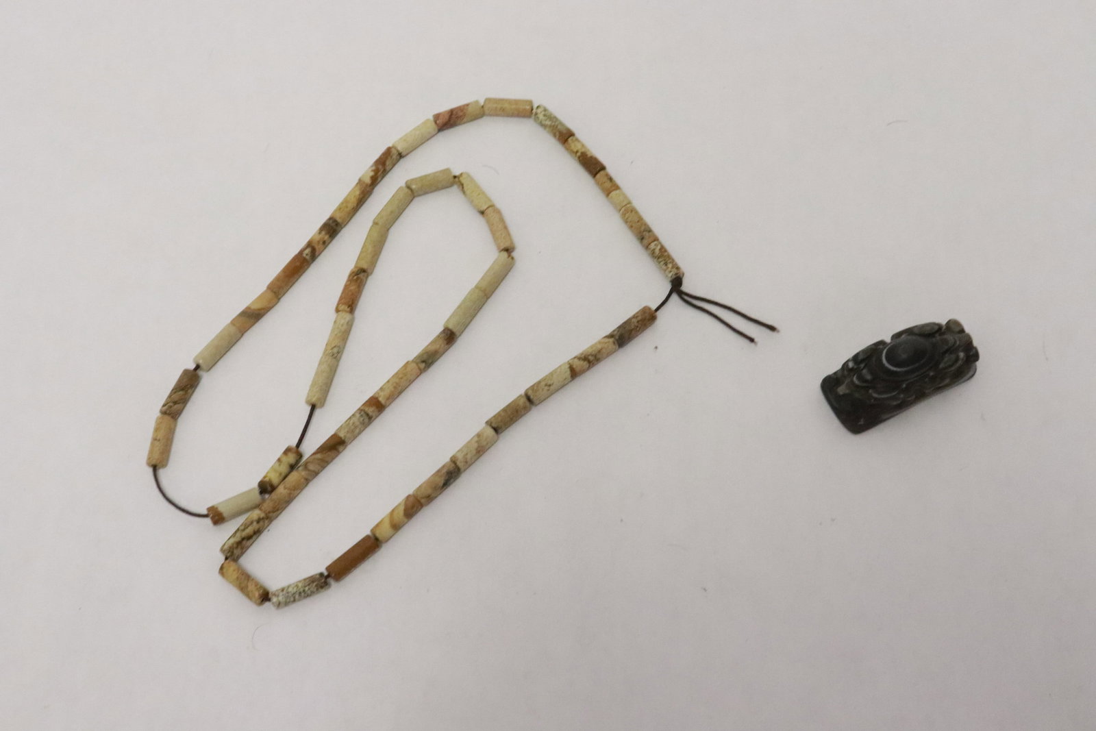 2 pieces: 2 pieces; 19th century agate carved pendant (0.75"x1.45"x0.68"), and an early jade carved tubular bead (0.5"x0.18"dia ea) necklace (24"L)