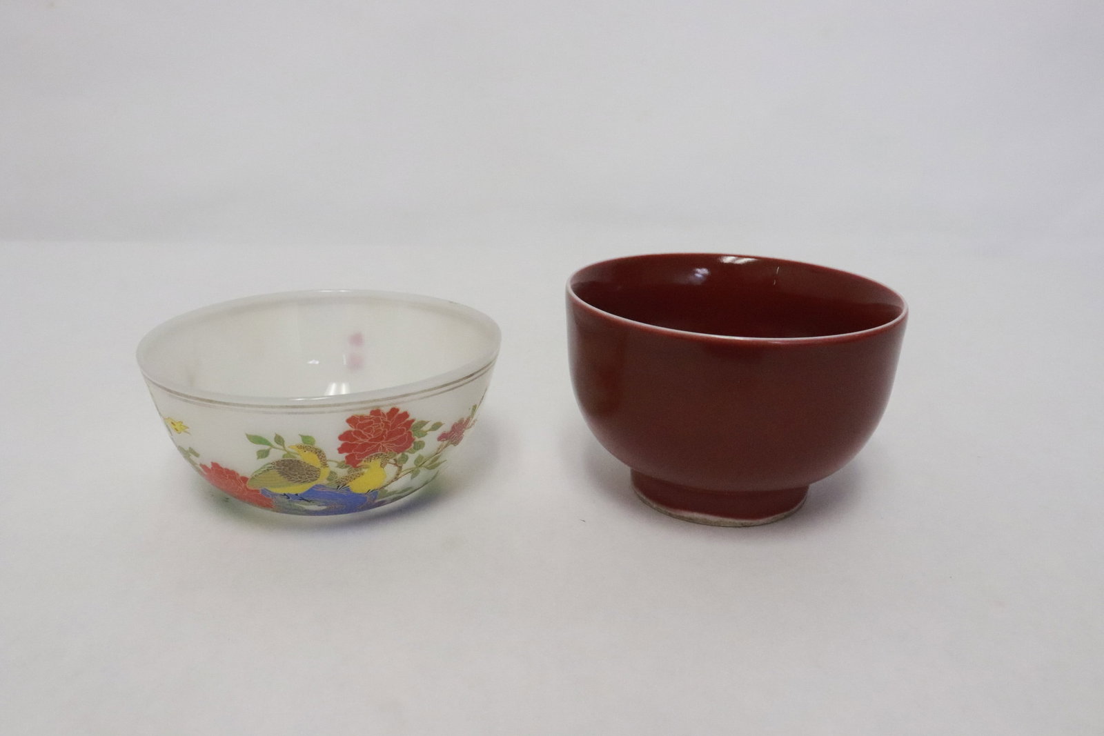 2 tea cups: 2 pieces; a red glazed porcelain tea cup (2"x3.15"dia), and an enamel on Peking glass tea cup (1.4"x3.35"dia)