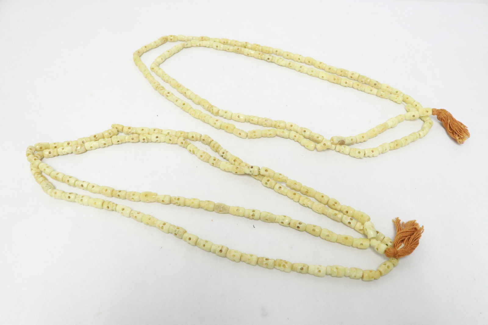 2 long bone carved necklaces w/ skull motif links: 2 long bone carved necklaces (52"L, 55"L) with skull motif links (0.5"x0.38"dia ea)